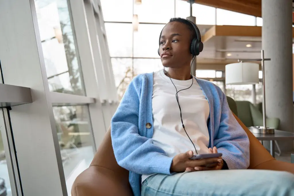 Woman at the airport listening to a podcast on her phone. Free meditation podcasts.