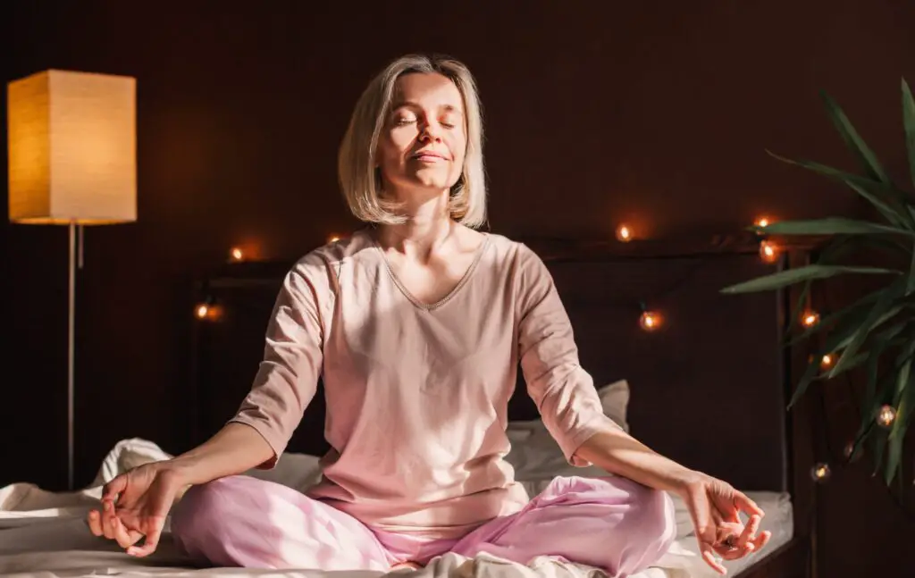 Can Meditation Heal The Brain? 4 Ways It Works Woman looking relaxed, meditating in bed. Can meditation heal the brain?